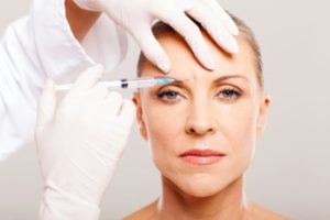A woman receiving botox in her forehead.