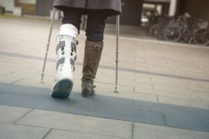 A man with his leg in a cast walks across a courtyard