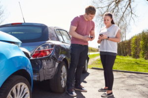 Two people exchanging details after a car accident