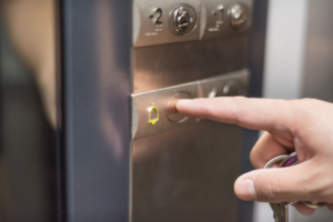 Person pressing emergency alarm button inside a lift