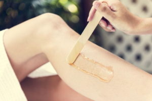 A person receiving waxing treatment on one of their legs