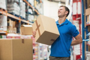 A man carrying a box and holding his back in pain due to a bulging disc