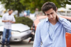 a person rubbing their neck after suffering whiplash in a car accident