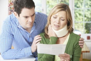 a man and woman looking at a piece of paper. the woman is wearing a neck brace