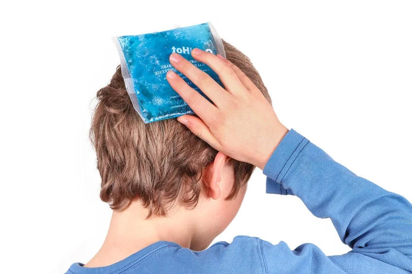 a child holding an ice pack to his head after suffering an injury 
