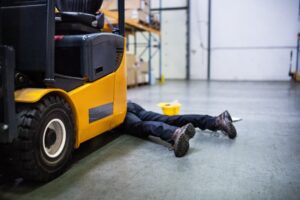 A man lying next to a fork lift truck after being injured in a forklift accident