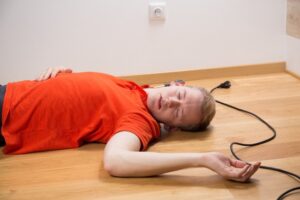 Injured person lying on the floor after tripping on a trailing lead hazard