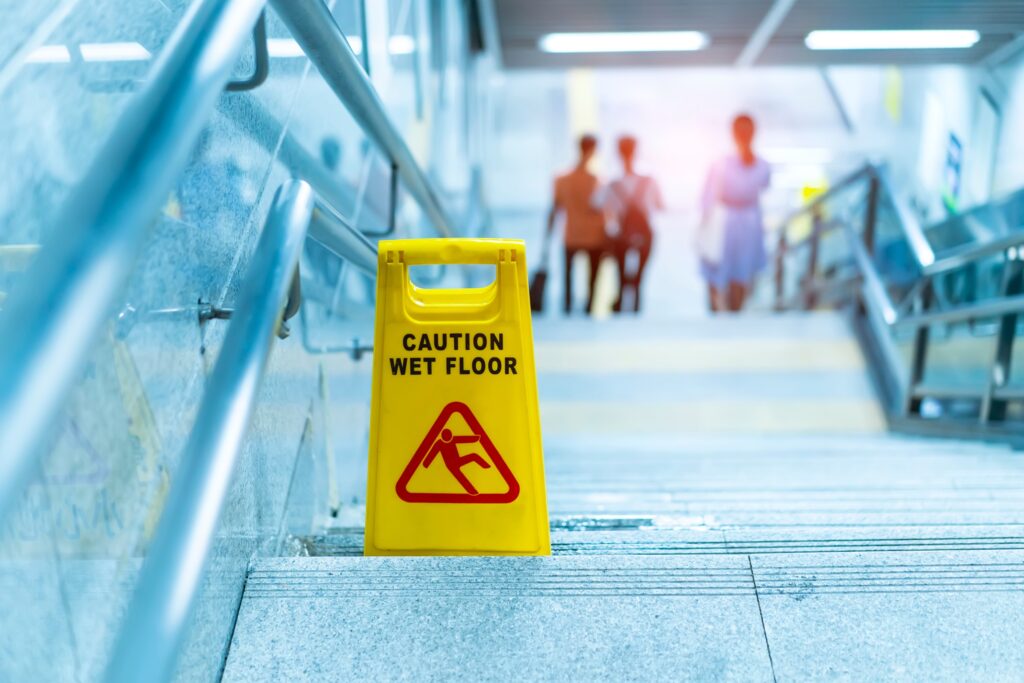 a wet floor sign positioned on a set of stairs with water upon it