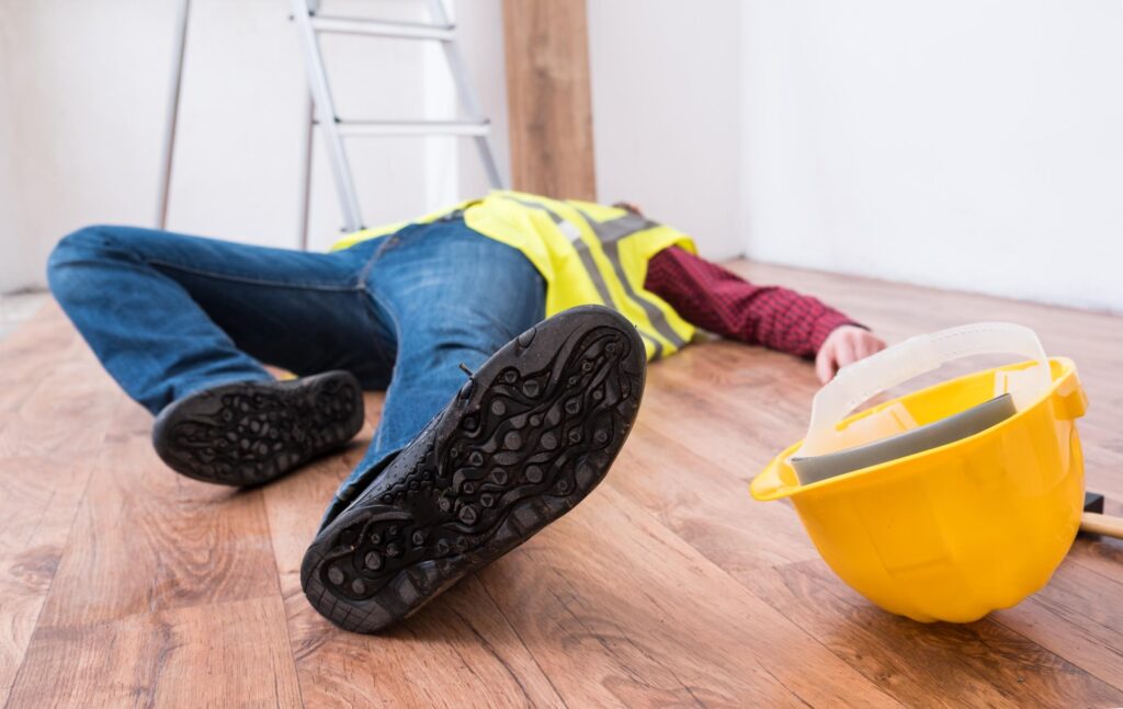 A man lying unconscious on the floor after a slip, trip or fall.