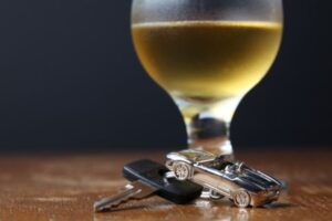 Car keys in front of a glass of white wine. 