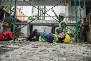 A construction worker lays injured on the ground as his co-worker calls for help