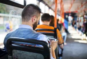 A man sitting on a bus looking at a tablet