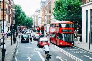 A red bus drives down a tree-lined street