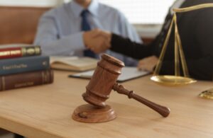 A criminal injuries compensation solicitor shaking hands with their client, with a gavel hammer and legal documents on the desk