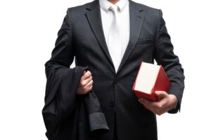 Man Holds A Black Robe And Large Book