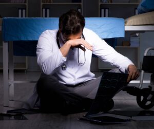 A doctor sits on the floor with his head in his hands