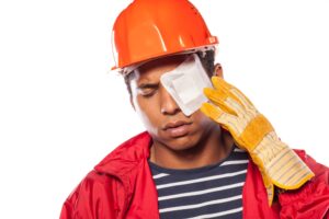 Sad looking male construction worker with a helmet and a plaster over his injured eye. 