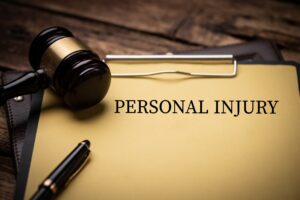 A clipboard holding a piece of paper with "personal injury" written on it. A judge's gavel and a pen sits on top of the paper.