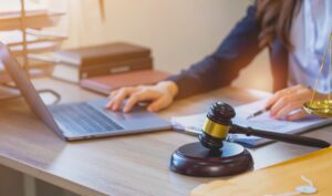 A Personal Injury Solicitor Makes Notes On Laptop And Notebook At Desk. 