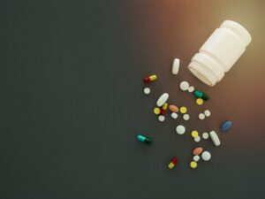 Medication tablets and a container spilled across a floor