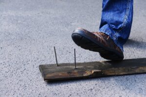 Someone about to step on some nails sticking out of a lone piece of wood