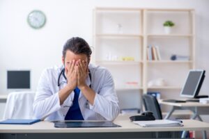 A doctor in distress with his head in his hands