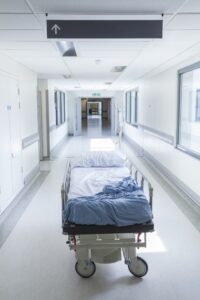 An empty hospital bed in a corridor.