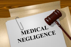 A wooden gavel lies on top of a paper file that says 'Medical Negligence'.