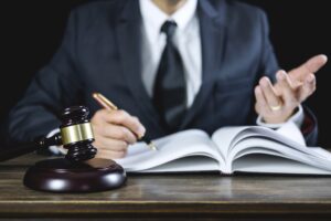 A GP misdiagnosis solicitor wearing a dark suit and tie sits at a desk. They are holding a pen.