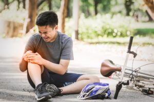 A cyclist clutching his injured leg after a cycling accident caused by road defects.