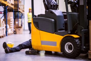 A worker's legs from behind a forklift after they've been hit by it.