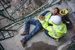A worker checking their colleague's pulse following a fatal work accident