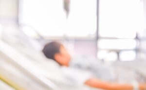 A blurry image of a patient lying in a hospital bed.