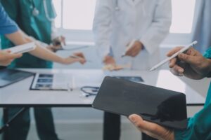 A group of professionals standing around a table and discussing medical care.