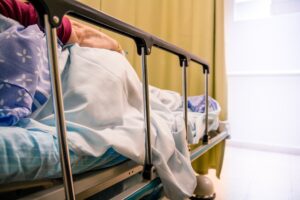 An elderly woman laying in a hospital bed with the rails up
