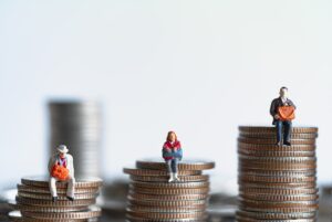Three stacks of coins at different heights with a person sat on each stack.
