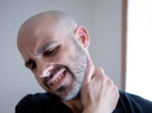 man holding neck in pain due to whiplash injury