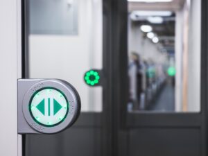 An automatic train door with the green open button visible in the foreground.