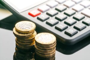 Two piles of coins sat next to a calculator.