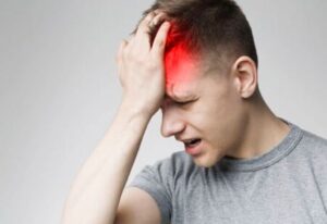 Man with concussion injury holds his forehead in pain