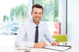 A smiling personal injury solicitor sat behind a desk.