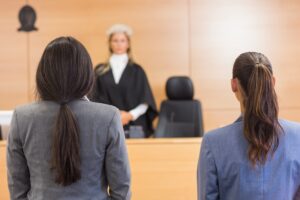 A train accident lawyer standing next to their client in a court, facing a judge who is visible in the background.