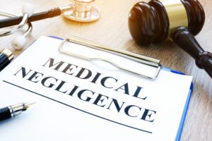 Clipboard with documents about a medical negligence claim on a table with a gavel. 
