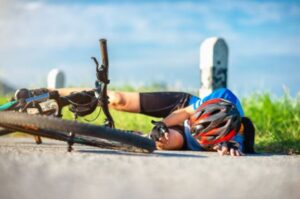 Injured cyclist lying on the ground next to their bicycle following a cycling accident