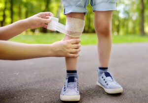 A child is having their knee bandaged. 