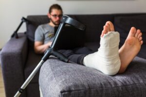 A man sits on a sofa with a broken leg.