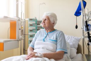 A senior patient sits in a hospital bed. 