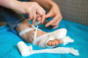 A person bandages a foot or toe injury. 