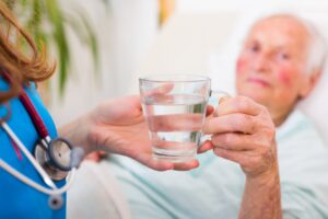 A healthcare professional brings a woman a glass of water. 