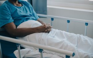 A patient lays on a hospital bed suffering from negligent care.